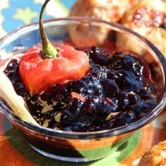 a glass bowl filled with blueberry sauce and topped with an orange bell pepper on top