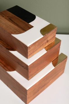 three pieces of wood are stacked on top of each other, one with white and gold accents