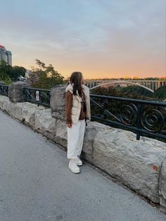 a woman standing on the side of a bridge