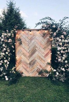 an outdoor ceremony area with flowers and greenery on the grass, surrounded by wooden planks