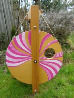 a wooden swing with a pink and yellow design on the front, sitting in grass