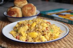 a white plate topped with food next to two bowls filled with eggs and rolls on top of a table