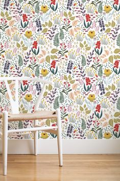 a white chair sitting in front of a wall with flowers and plants painted on it