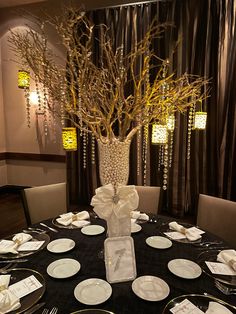 the table is set with white plates and silverware, as well as a vase filled with branches