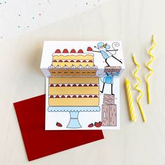 a birthday card with a cartoon cake on it and two candles next to the card