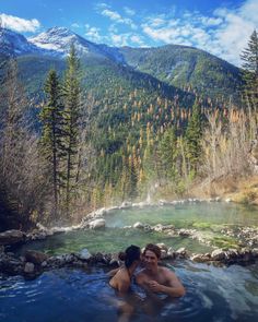 two people in a hot tub with mountains in the background