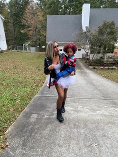 a woman is holding a doll on the sidewalk