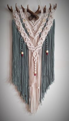 a wall hanging with deer antlers and tassels on it's sides