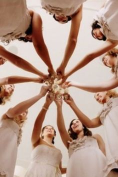 a group of bridesmaids standing in a circle holding their hands together to form a star