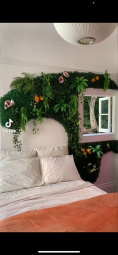 a bed covered in lots of green plants next to a window with a mirror above it