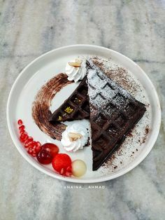 a white plate topped with two pieces of chocolate cake next to berries and whipped cream