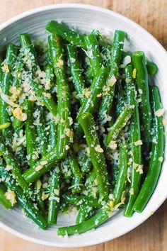 a white bowl filled with green beans covered in seasoning