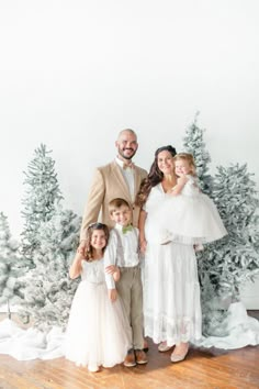 a family posing for a photo in front of christmas trees