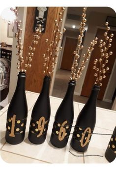 four black bottles with gold numbers on them