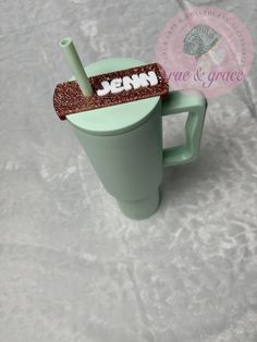 a green cup with a straw in it and a name tag on the handle that says jenny