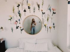 a woman taking a selfie in front of a mirror with flowers on the wall