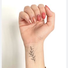 a woman's hand with a small flower tattoo on her left wrist and pink manicures