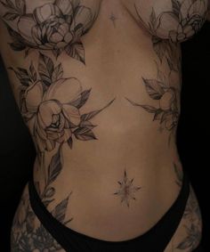 a woman's stomach with flowers and stars tattooed on her side, showing the back