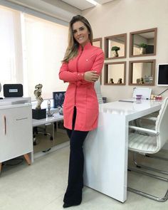 a woman standing in front of a desk with her arms crossed and looking at the camera