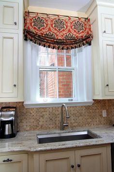 a kitchen window with an orange and black valance over the sink in front of it