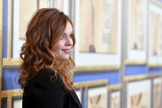 a woman standing in front of a wall with paintings on it's sides and looking off to the side