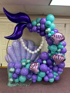 a purple and blue balloon arch with mermaid decorations