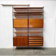 a tall wooden shelf with drawers and shelves on each side, against a white wall