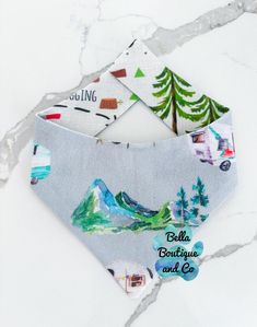 two bandanas with trees and mountains on them, one has a name tag attached to it