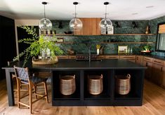 a kitchen with wooden floors and black counter tops, two hanging lights above the island