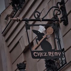 a restaurant sign hanging off the side of a building with a chef's hat on it