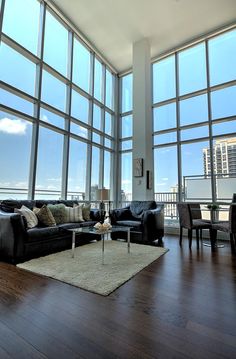 a living room filled with furniture and large windows overlooking the cityscape in the distance