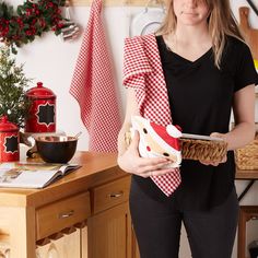 a woman in black shirt holding a basket with food on it and christmas decorations behind her