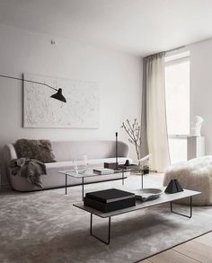 a modern living room with white walls and carpeted flooring, two couches, a coffee table and a painting on the wall