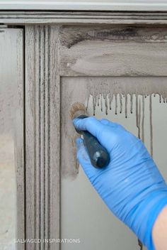 a person in blue gloves and latex gloves painting a wooden door with white paint