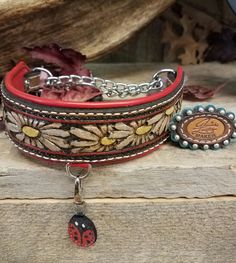 a close up of a dog collar on a wooden surface with flowers and ladybug charms