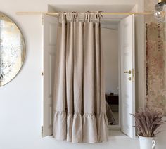 an open door leading to a bathroom with a mirror on the wall and curtains hanging in front of it