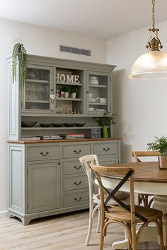 a dining room table and chairs with a hutch in the background