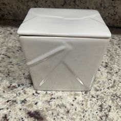 a white square object sitting on top of a marble counter next to a black and white wall