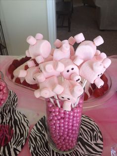 there is a vase filled with pink candy and marshmallows on the table