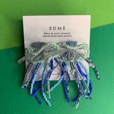 several pieces of blue and white beaded hair clips sitting on top of a green table