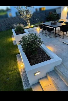 an outdoor dining area is lit up at night with lights on the table and chairs