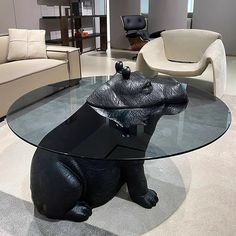 a glass table with a black bear statue on it's base in a living room