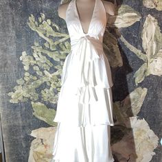 a woman's white dress on display in front of a floral wallpapered background