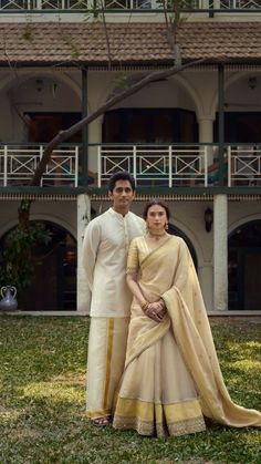 a man and woman standing next to each other in front of a building with grass