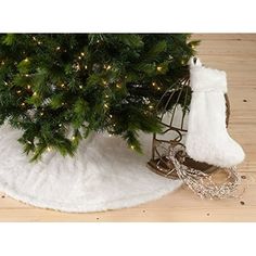 a small christmas tree with white fur and lights next to a metal birdcage