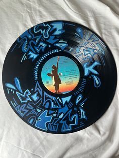 a black and blue record with graffiti on it's side sitting on a white sheet