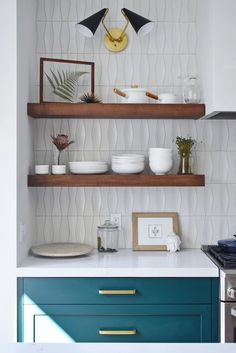 a kitchen with open shelving and blue cabinets in the corner, along with brass pulls