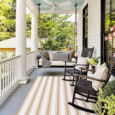 a porch with rocking chairs and striped rug