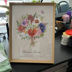 a painting on a table with flowers and butterflies in the frame next to some other items