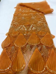 an orange dress with gold sequins on the bottom, and fringe around it